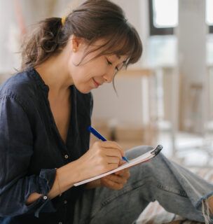 A women's makes notes in a notebook.