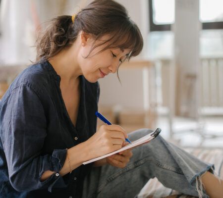 A women's makes notes in a notebook.