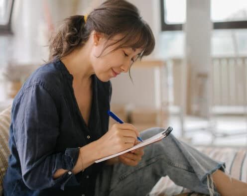 A women's makes notes in a notebook.