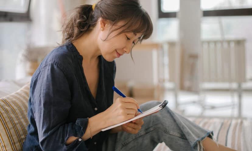 A women's makes notes in a notebook.