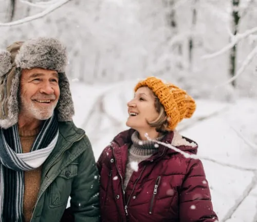 Photo of an elderly couple who enjoy walking together on a cold snowy day while holding hands