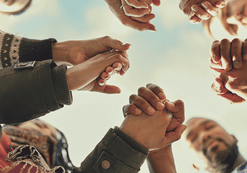 A circle of people hold hands