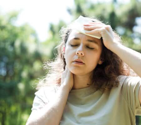 Young woman having hot flash and sweating in a warm summer day
