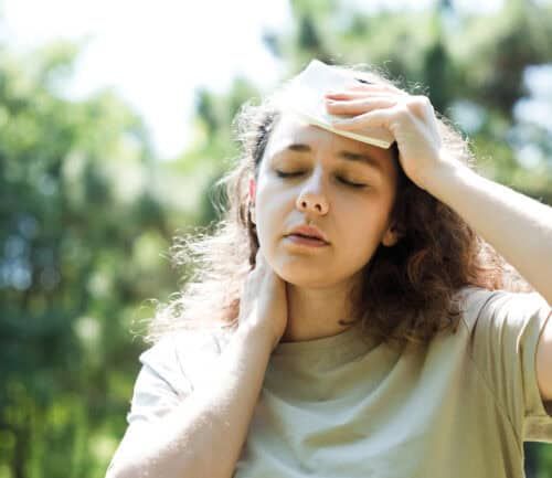 Young woman having hot flash and sweating in a warm summer day