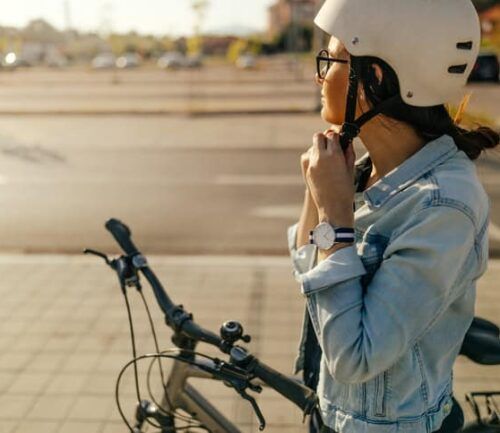 Young woman putting her helmet, preparing for the bike ride
