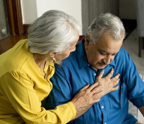 Wife comforting her husband suffering with severe chest pain