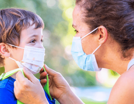 A mother adjusts her son's face mask