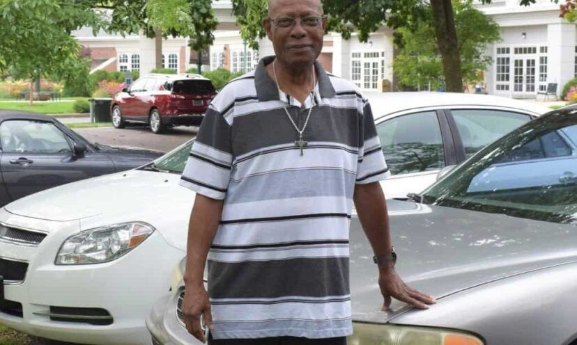 Patient Darryl stands in the parking lot, touching his car