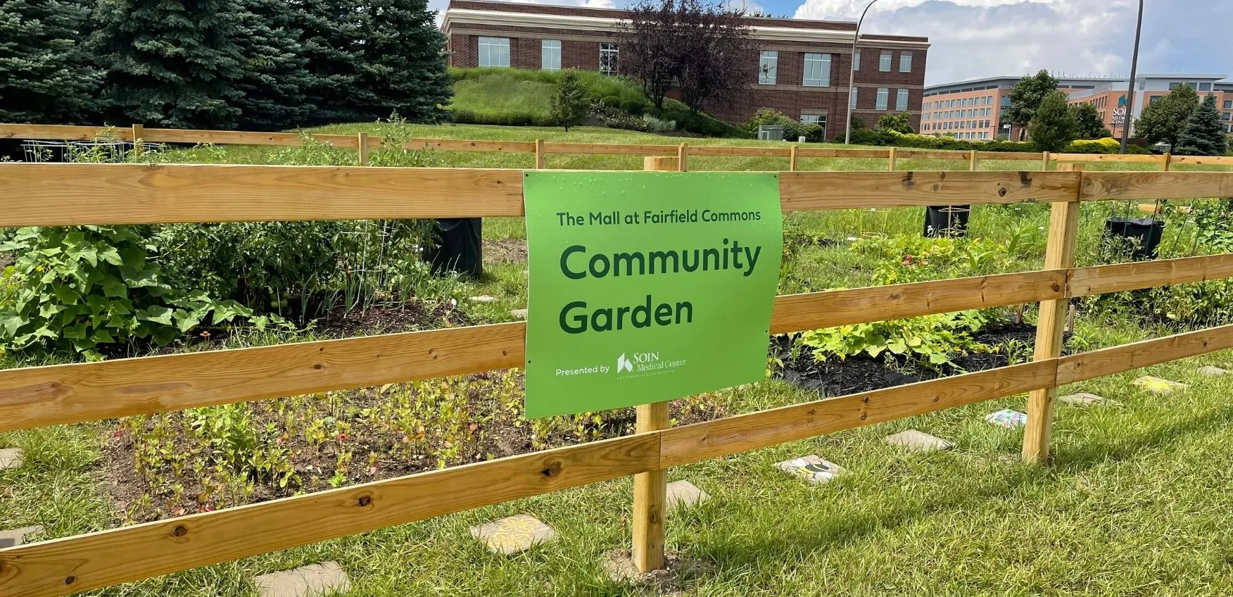 Community garden sign with plants in background.