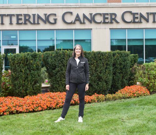 Beth stands in front of Kettering Cancer Center sign