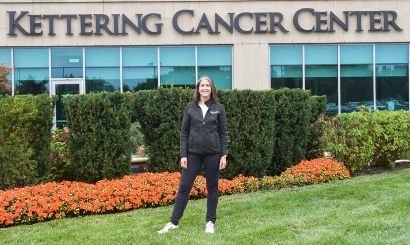 Beth stands in front of Kettering Cancer Center sign