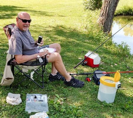Don sits by water preparing to fish with iPod in hand