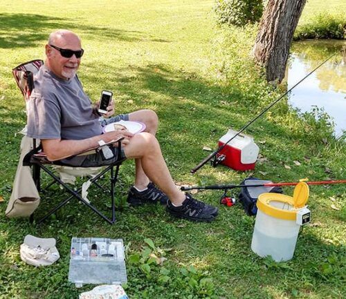 Don sits by water preparing to fish with iPod in hand