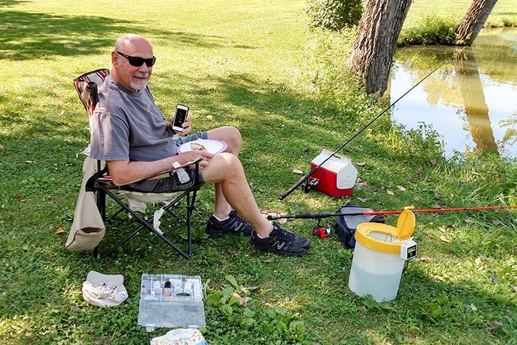 Don sits by water preparing to fish with iPod in hand