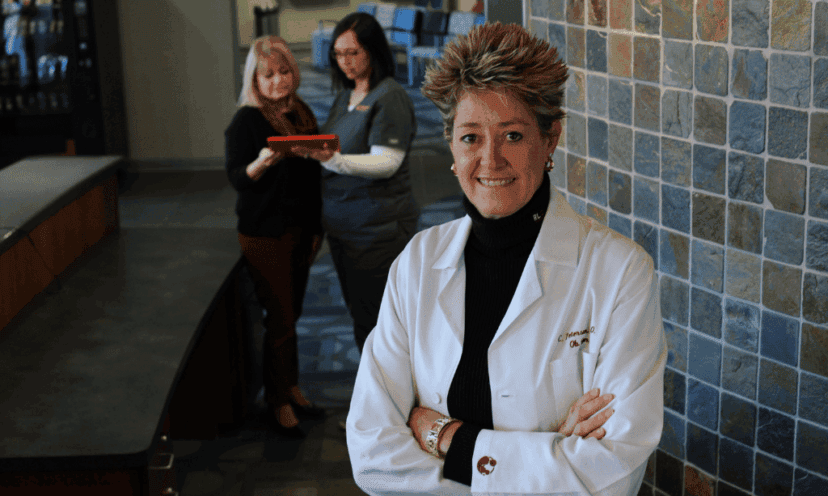 Dr. Peterson stands with arms cross, two women stand behind her