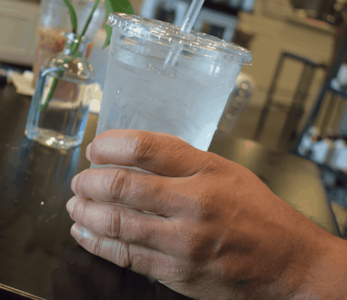 Man holds cup of water at table