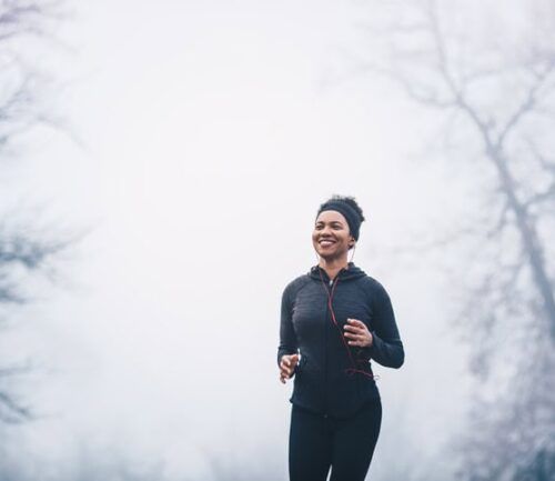 A woman jogging in the park forming healthy winter habits