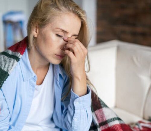 Woman pinches bridge of nose with stress