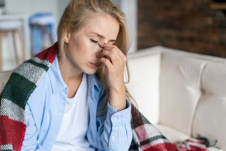Woman pinches bridge of nose with stress