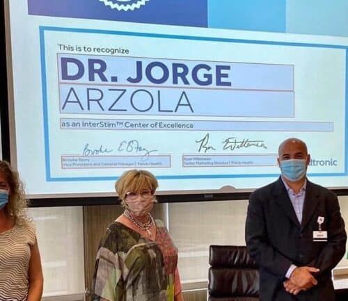 Dr. Jorge Arzola and other members of Urology pose in front of award for InterStim Center of Excellence