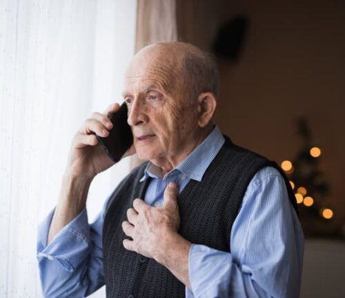 Senior talking on phone with a serious face expression and holding the chest