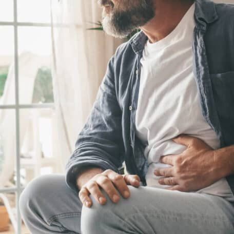 Man holding his stomach in his home.