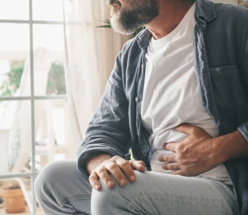 Man holding his stomach in his home.