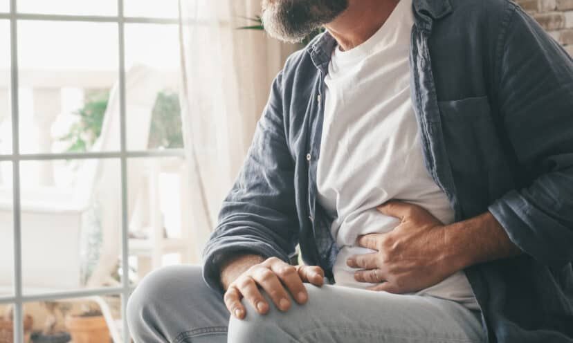 Man holding his stomach in his home.