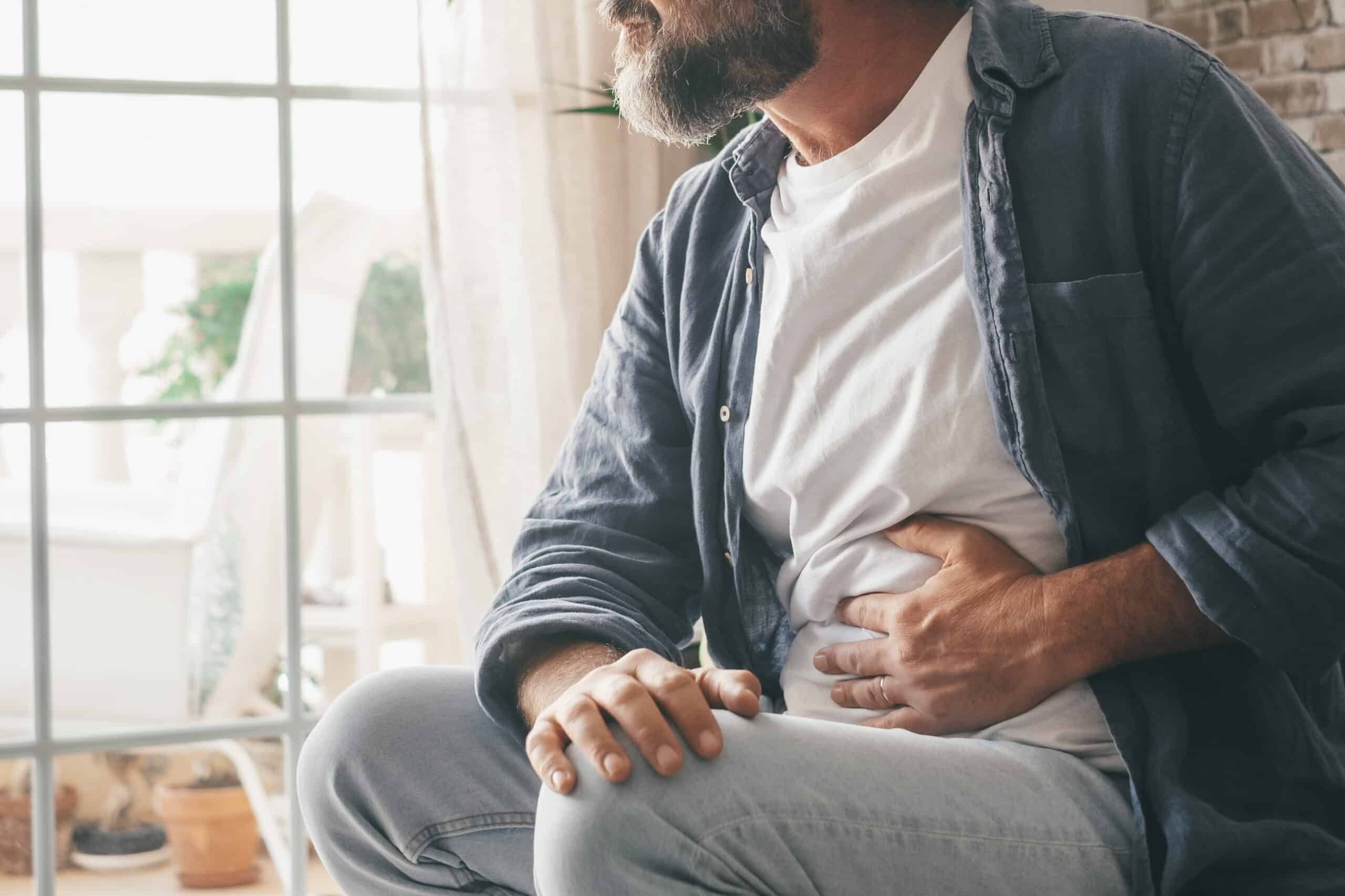 Man holding his stomach in his home.