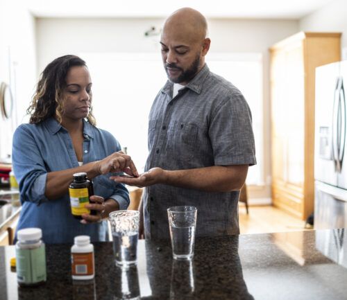 Husband and wife taking vitamins at home