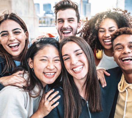 Happy group of young people smiling at camera outdoors - Smiling friends having fun hanging out on city street - University students standing together in college campus - Friendship and youth concept