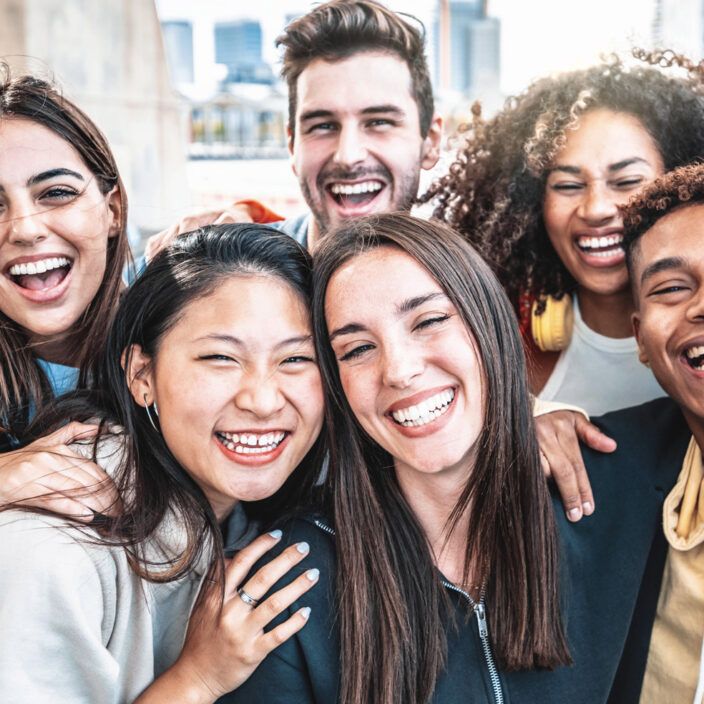 Happy group of young people smiling at camera outdoors - Smiling friends having fun hanging out on city street - University students standing together in college campus - Friendship and youth concept
