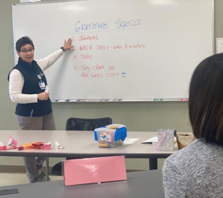 Julie Manuel teaches person about gratitude in front of a whiteboard