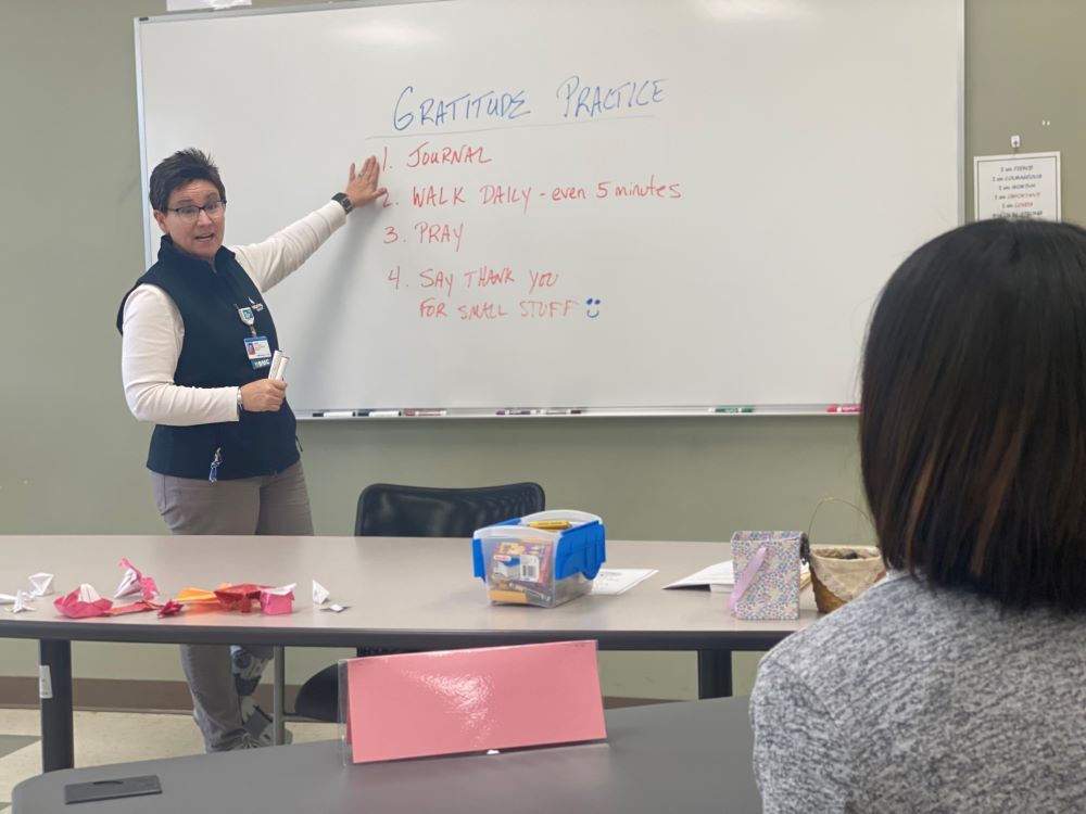 Julie Manuel teaches person about gratitude in front of a whiteboard