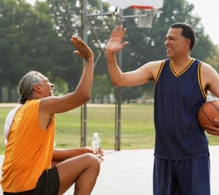 Two men high-fiving at a basketball court outside