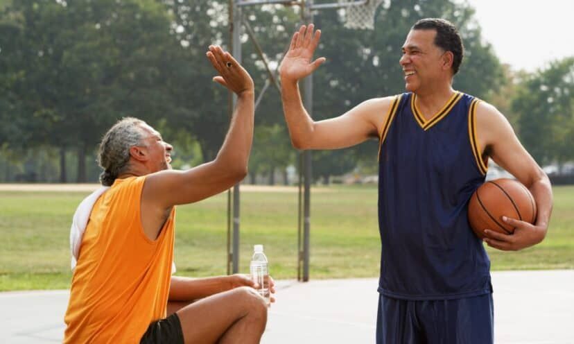 Two men high-fiving at a basketball court outside