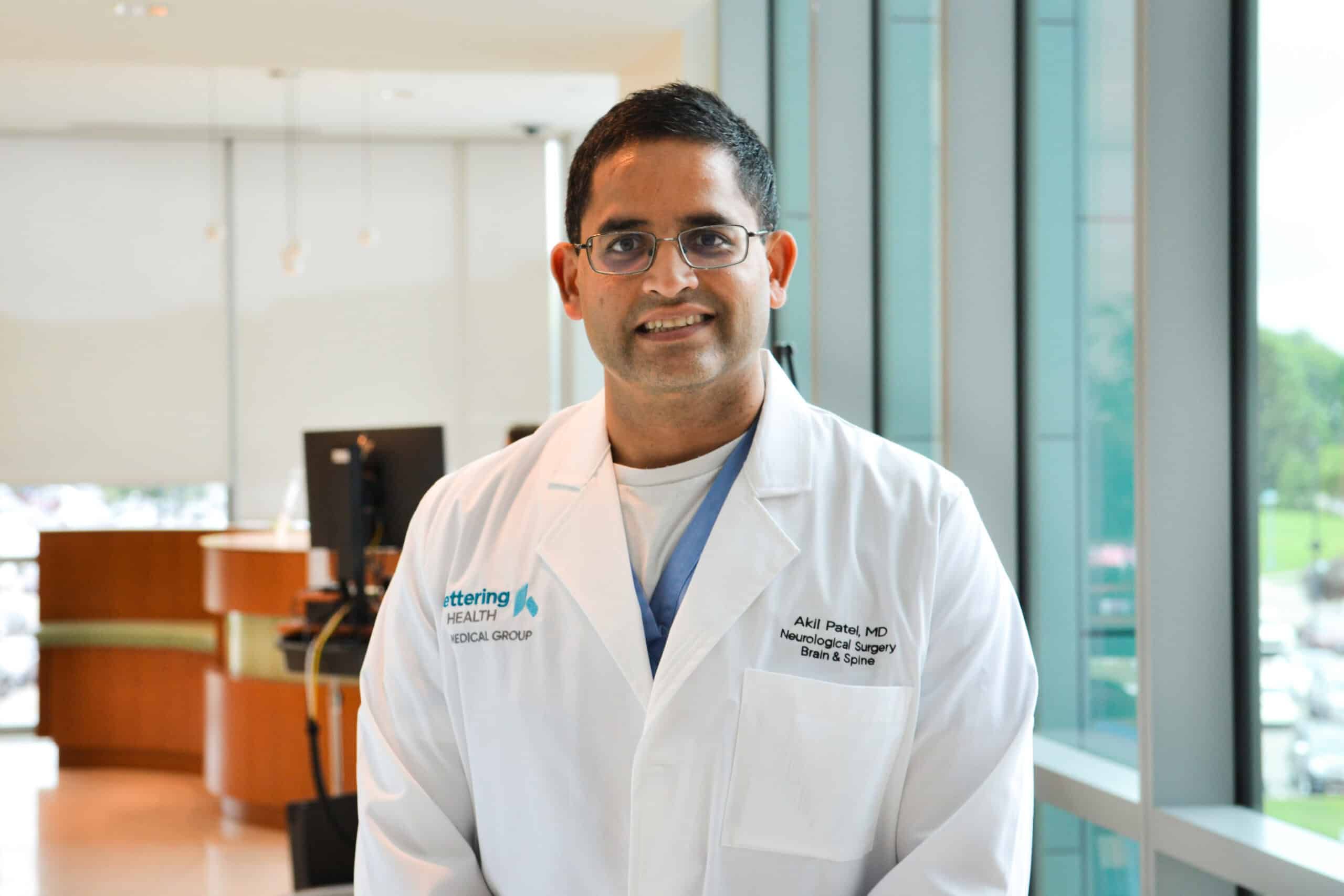 Dr. Akil Patel smiling at the camera in clinical hallway