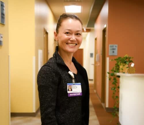 Dr. Melissa Butler standing in hallway, smiling at camera