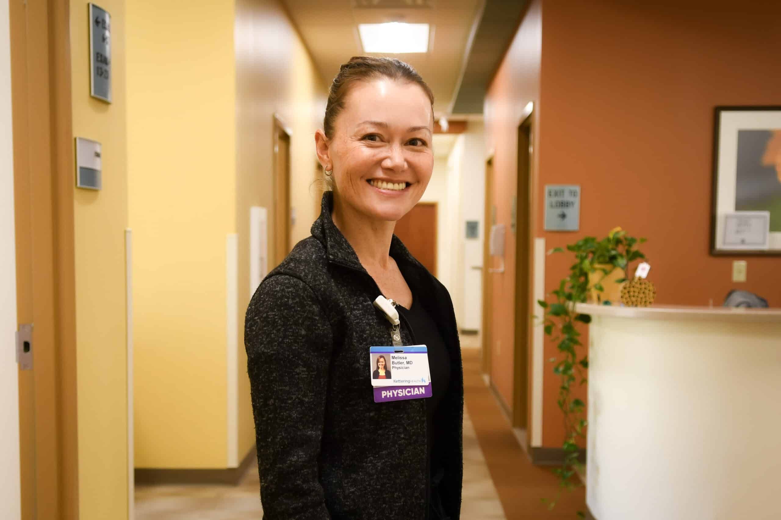 Dr. Melissa Butler standing in hallway, smiling at camera