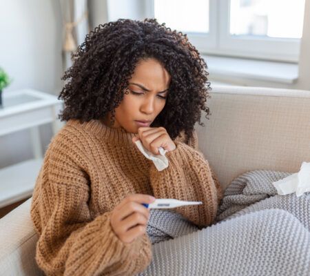 Woman on the couch checking her temperature