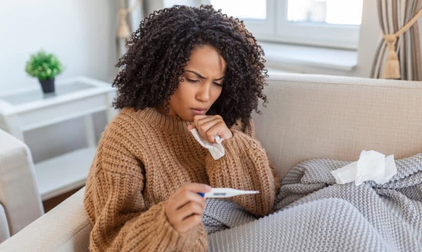 Woman on the couch checking her temperature