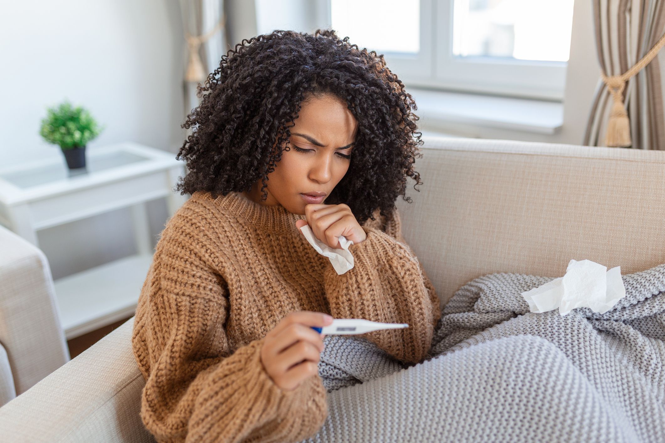 Woman on the couch checking her temperature