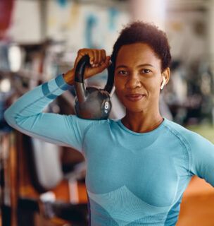 Black female athlete with kettlebell in a gym looking at camera.