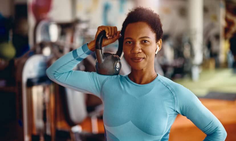 Black female athlete with kettlebell in a gym looking at camera.