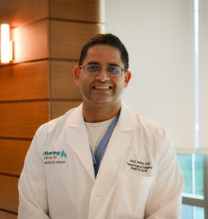 Dr. Akil Patel standing and smiling.