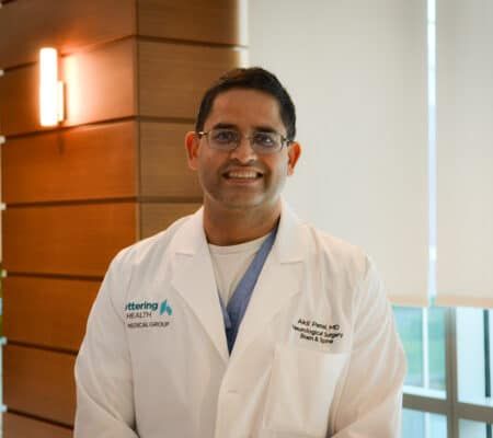 Dr. Akil Patel standing and smiling.