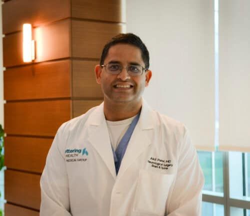 Dr. Akil Patel standing and smiling.