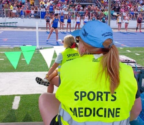 Sports medicine provider sitting on sidelines