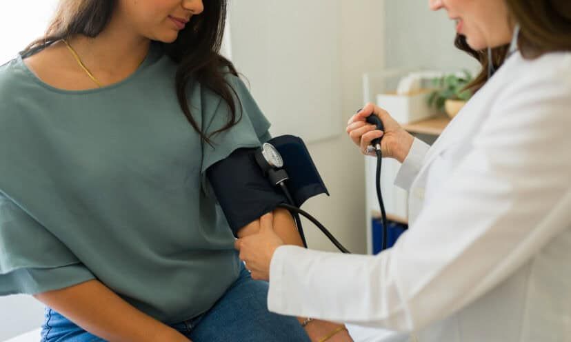 Closeup of a doctor measuring blood pressure of young woman during medical check-up