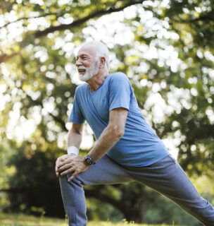 Shot of a senior man standing alone and stretching during his outdoor workout